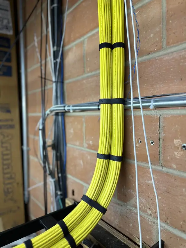 Yellow Cat6A cable bundle dressed on brick wall