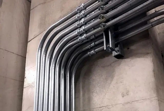 Parallel EMT conduit bends on a concrete wall with strut support